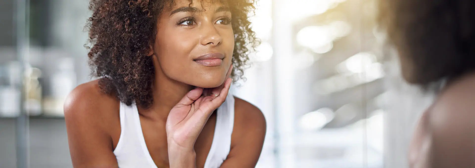 Femme à la peau lumineuse se regardant dans le miroir – bien-être et soins visage naturels Kadalys