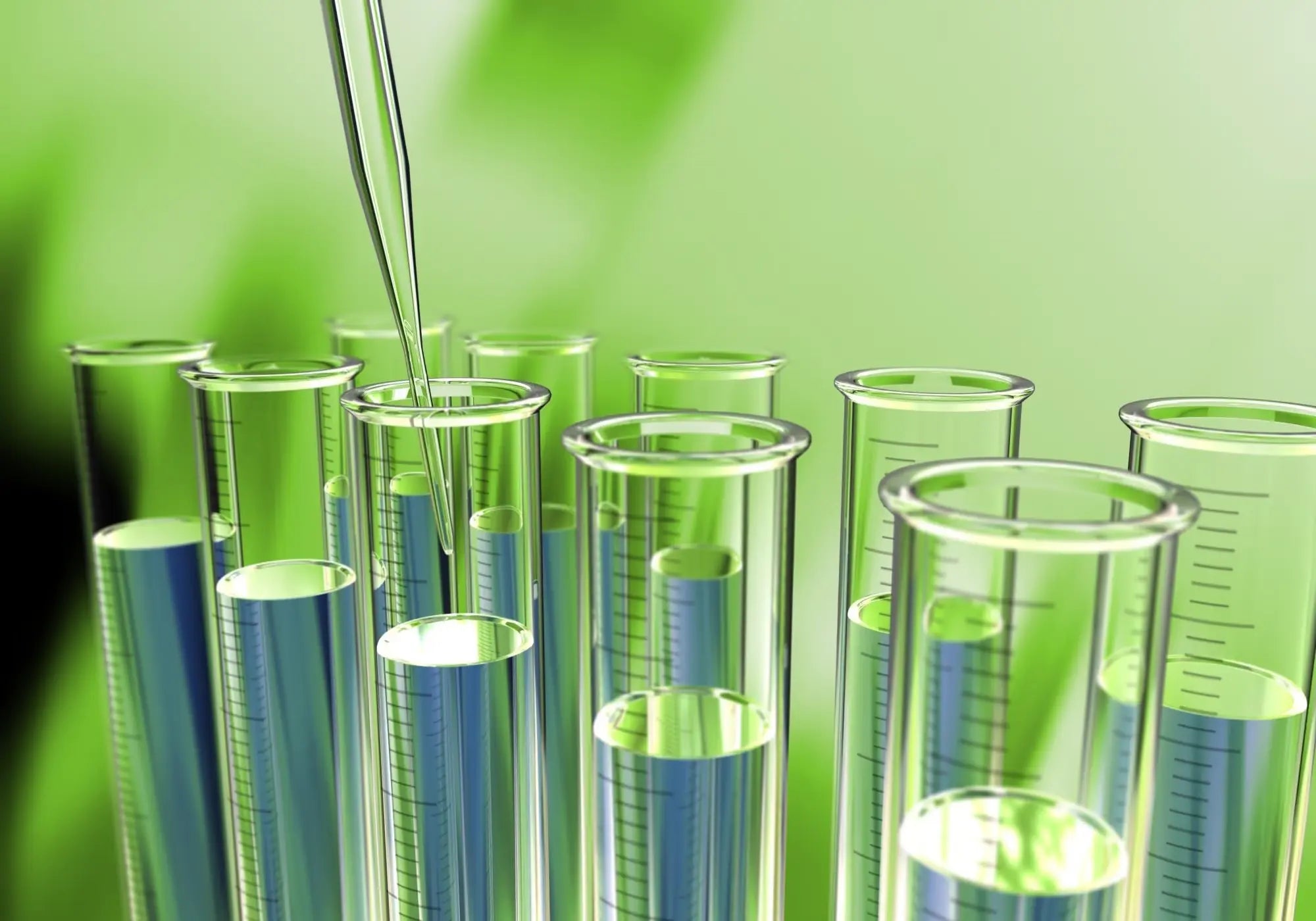 Pipette versant un liquide vert dans des tubes à essai, représentant la formulation naturelle des soins.